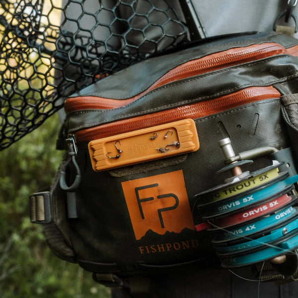 Fishing bag with visible brand logo and fishing equipment on a blurred natural background