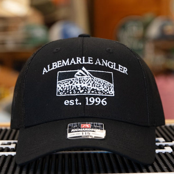 Black cap with branding on a glass table in a store setting