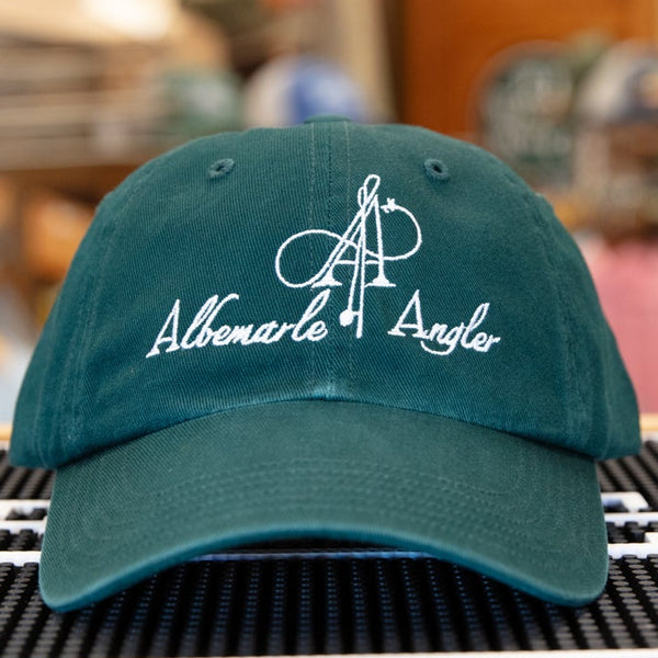 Green cap with branding on a black mat in a store setting
