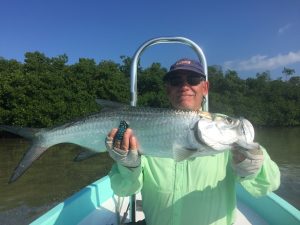Angler with a small tarpon caught from Belize River Lodge.