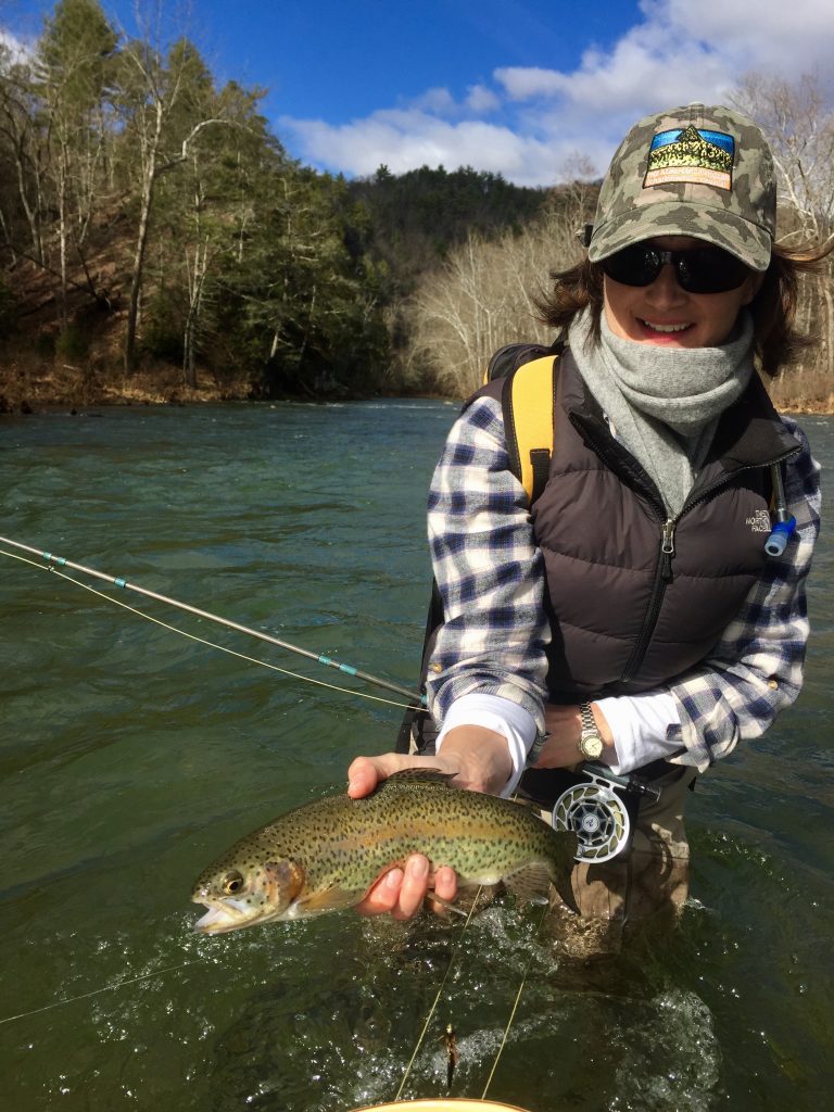 Happy female angler with a rainbow trout caught during a ladies fly fishing class on Big Bend Farm.
