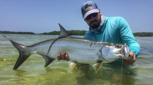 Angler in the water with a small tarpon caught while fishing with La Pescadora Lodge in Punta Allen Mexico.