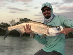 Angler with a small tarpon at sunset in Cuba.