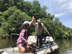 Female angler and fishing guide in boat flaoting a Virginia smallmouth river.