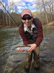 A happy female angler holding a nice rainbow caught during the ladies fly fishing lesson with a Virginia fishing guide.